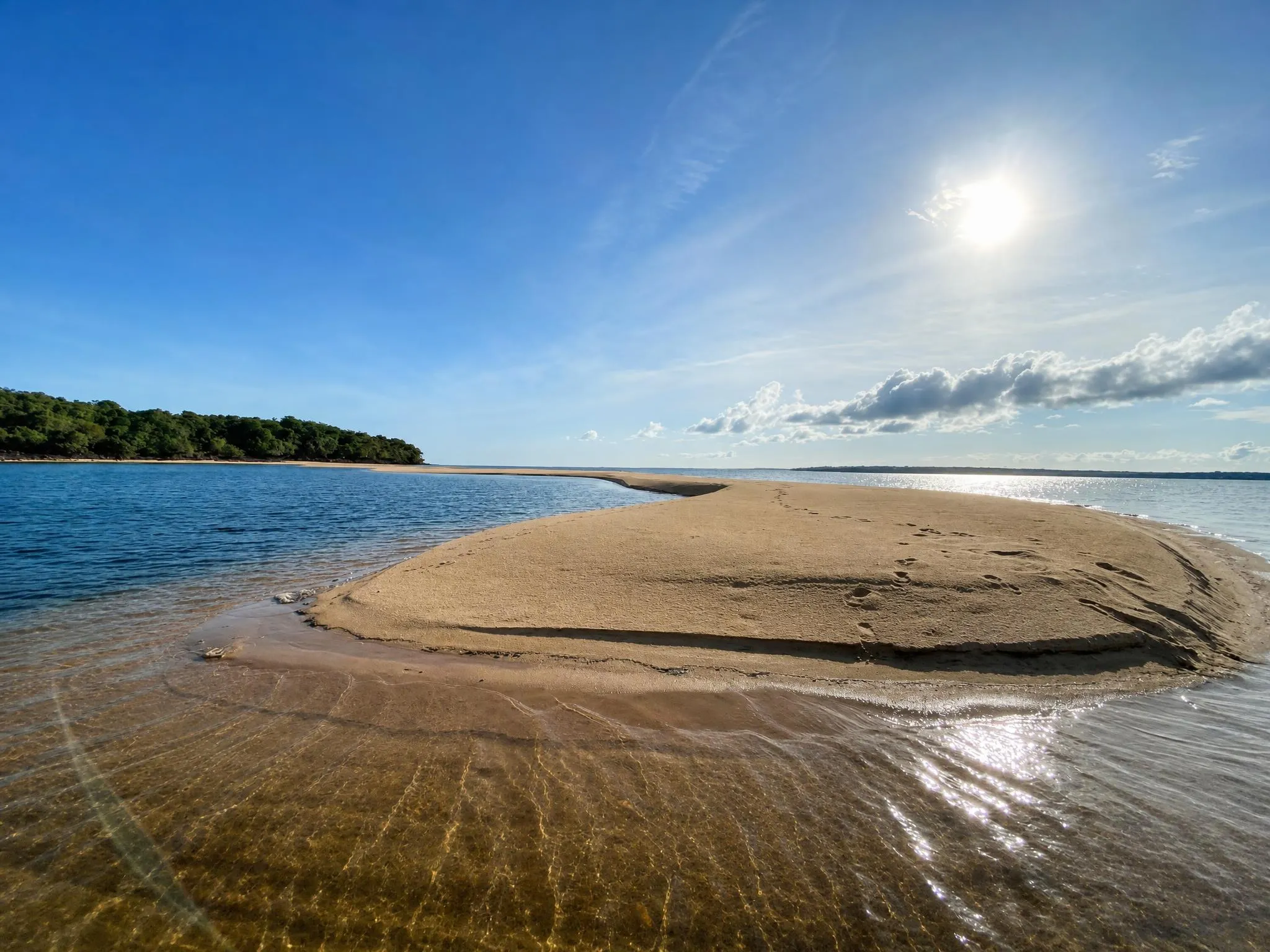 Banco de areia dourada dentro do rio, com a água rasa tão clara que o fundo aparece ondulado pela luz