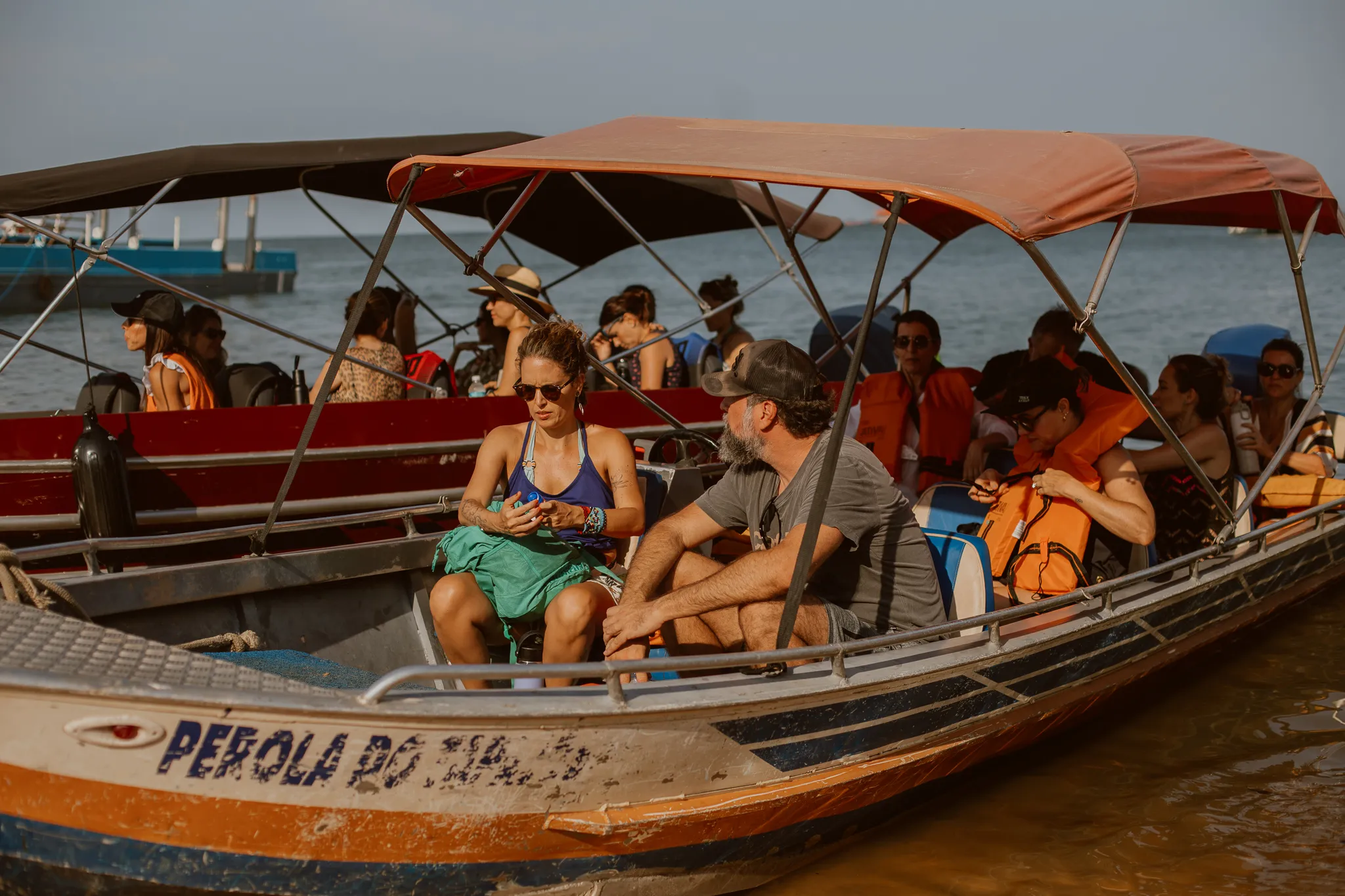 Guests in life vests boarding the boat Pérola do Tapajós, moored by the sand